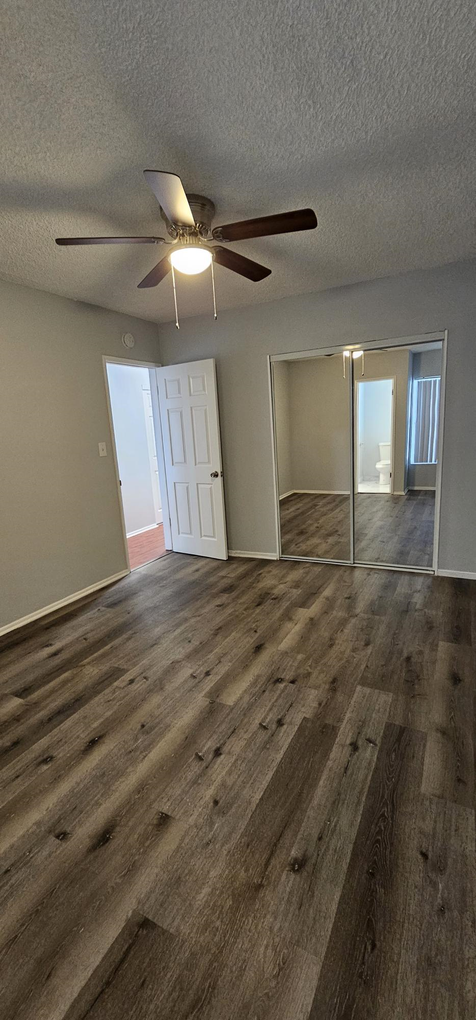 an empty living room with wood floors and a ceiling fan