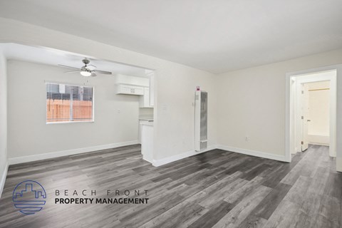 the living room of an apartment with wood flooring and a ceiling fan