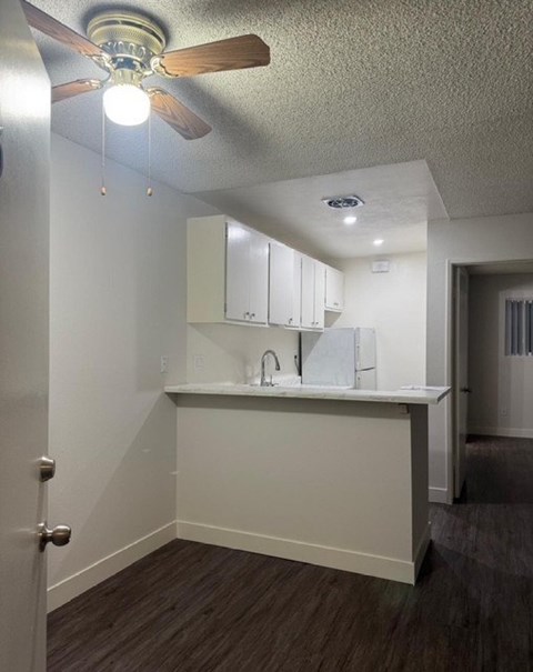 A kitchen with white cabinets and a ceiling fan.