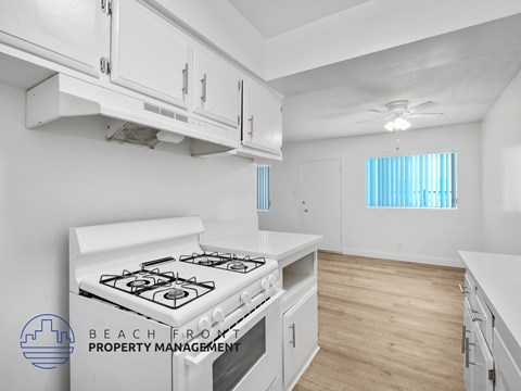 A kitchen with a stove top oven and a window with blinds.