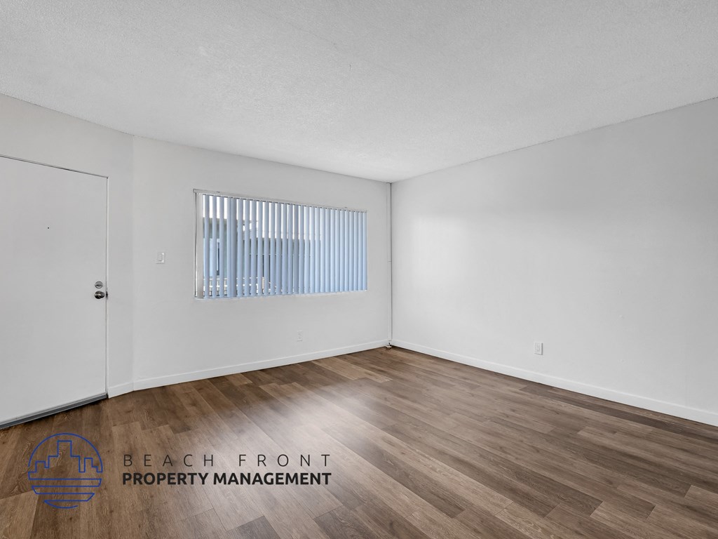 A room with wooden flooring and a window with blinds.