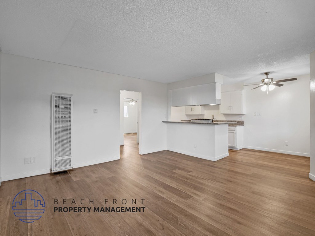 A spacious room with wooden flooring and a ceiling fan.