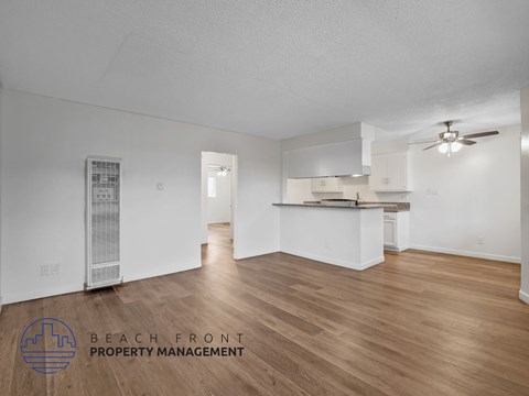 A spacious room with wooden flooring and a ceiling fan.