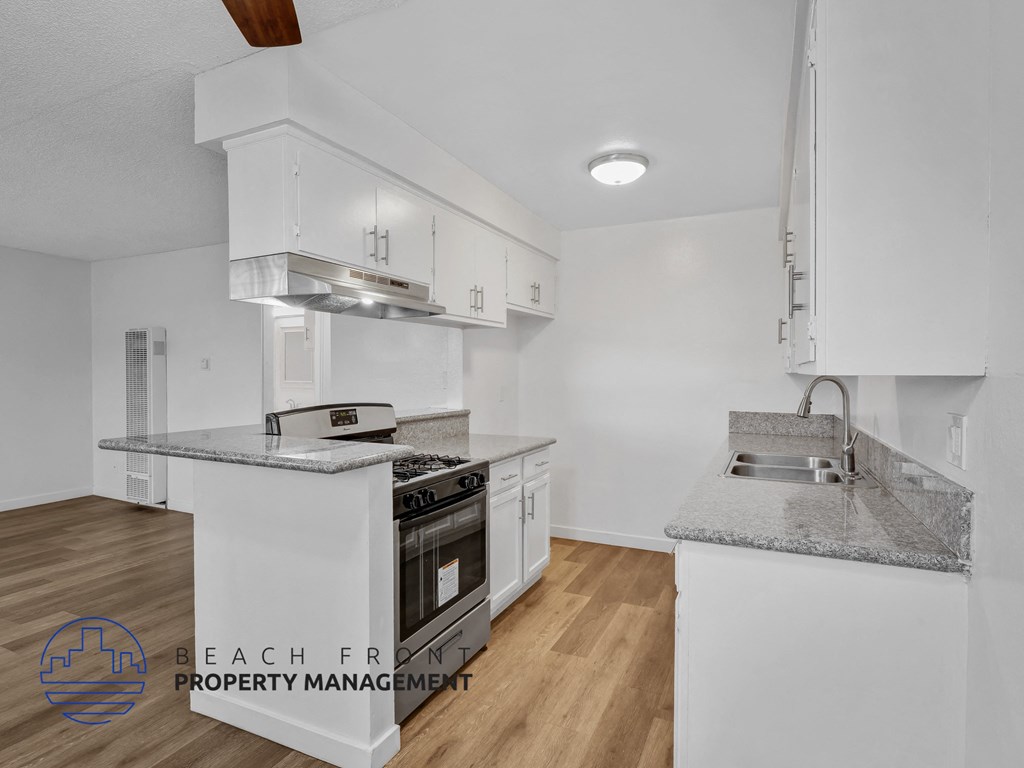 A modern kitchen with white cabinets and a granite countertop.