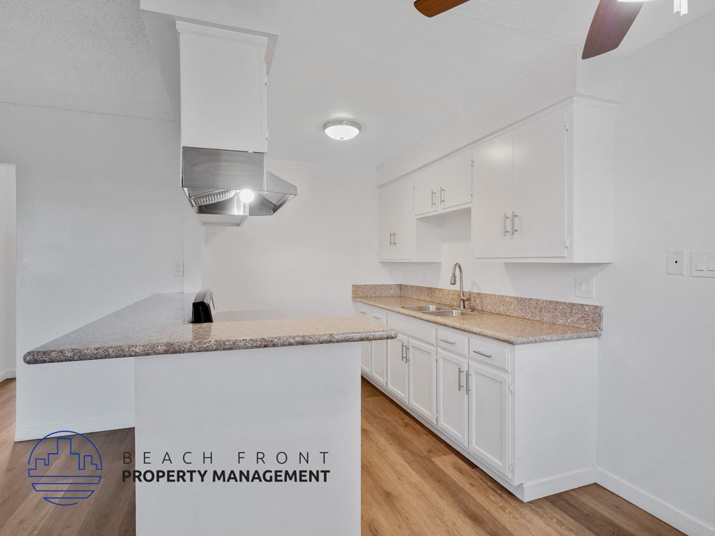 A kitchen with white cabinets and a granite countertop.
