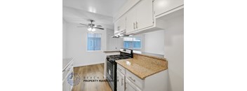 A kitchen with a black stove top oven and a counter top with a brown granite counter top.