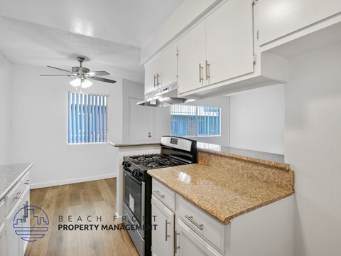 A kitchen with a black stove top oven and a counter top with a brown granite counter top.