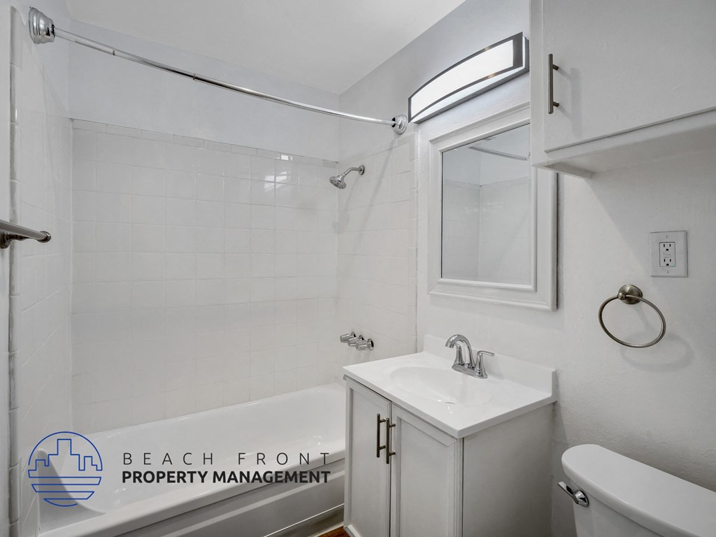 A white bathroom with a shower, sink, and toilet.
