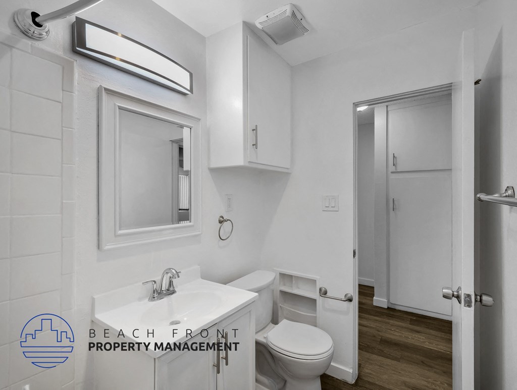 A bathroom with a toilet, sink, and mirror.