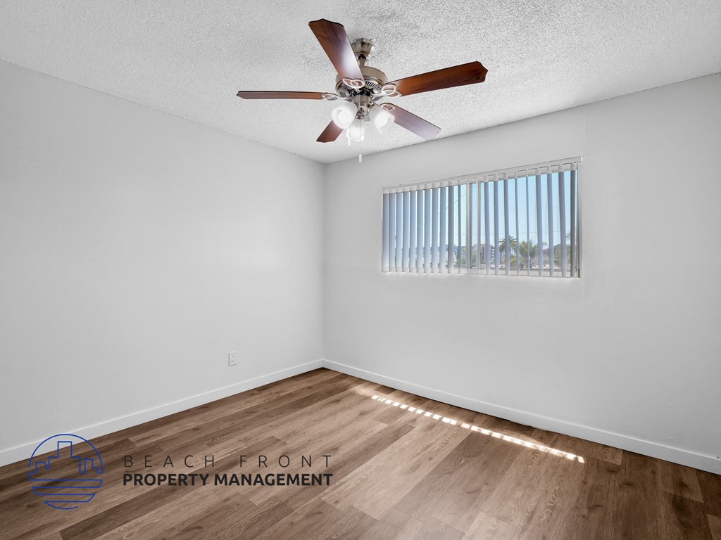 A room with a ceiling fan and wooden flooring.
