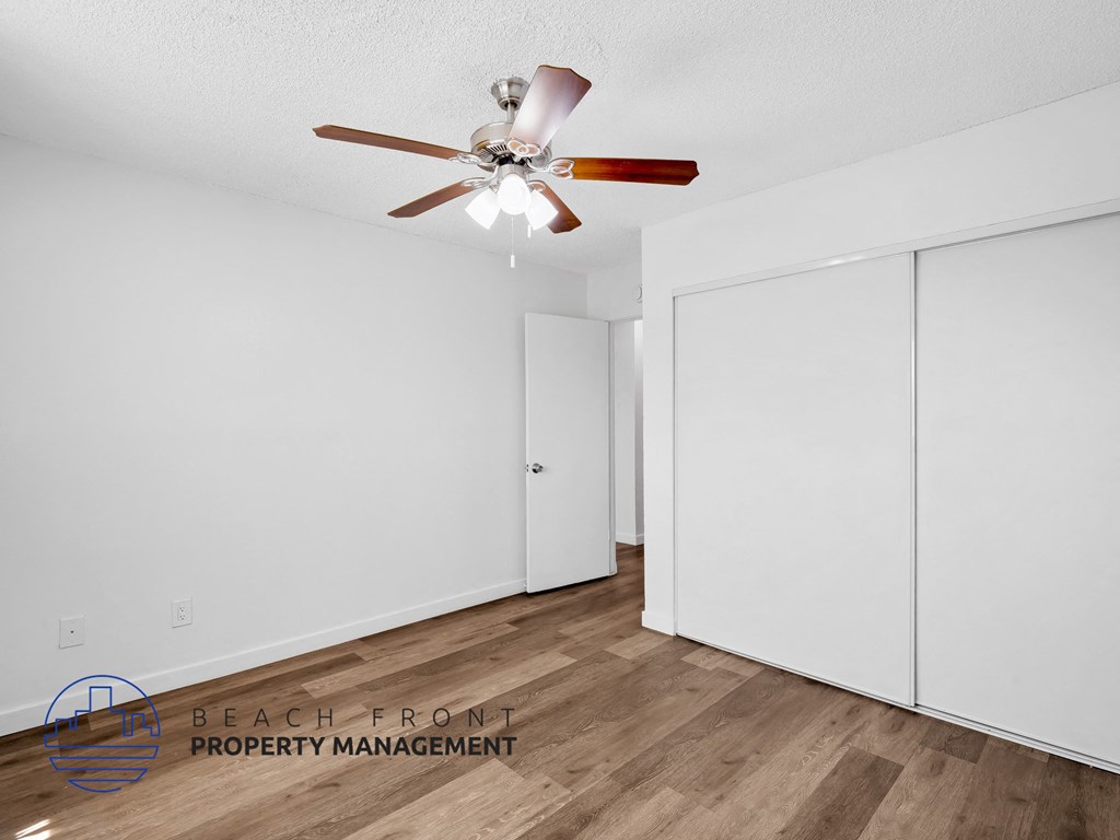 A room with a ceiling fan and wooden flooring.