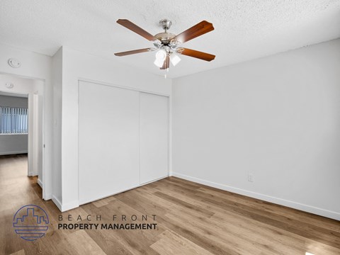 A room with a ceiling fan and a logo for Beach Front Property Management.