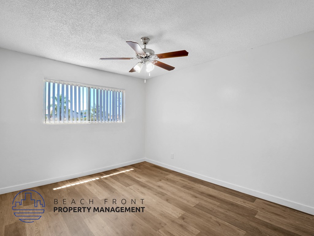 A room with a ceiling fan and wooden flooring.