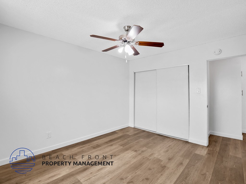A room with a ceiling fan and wooden flooring.