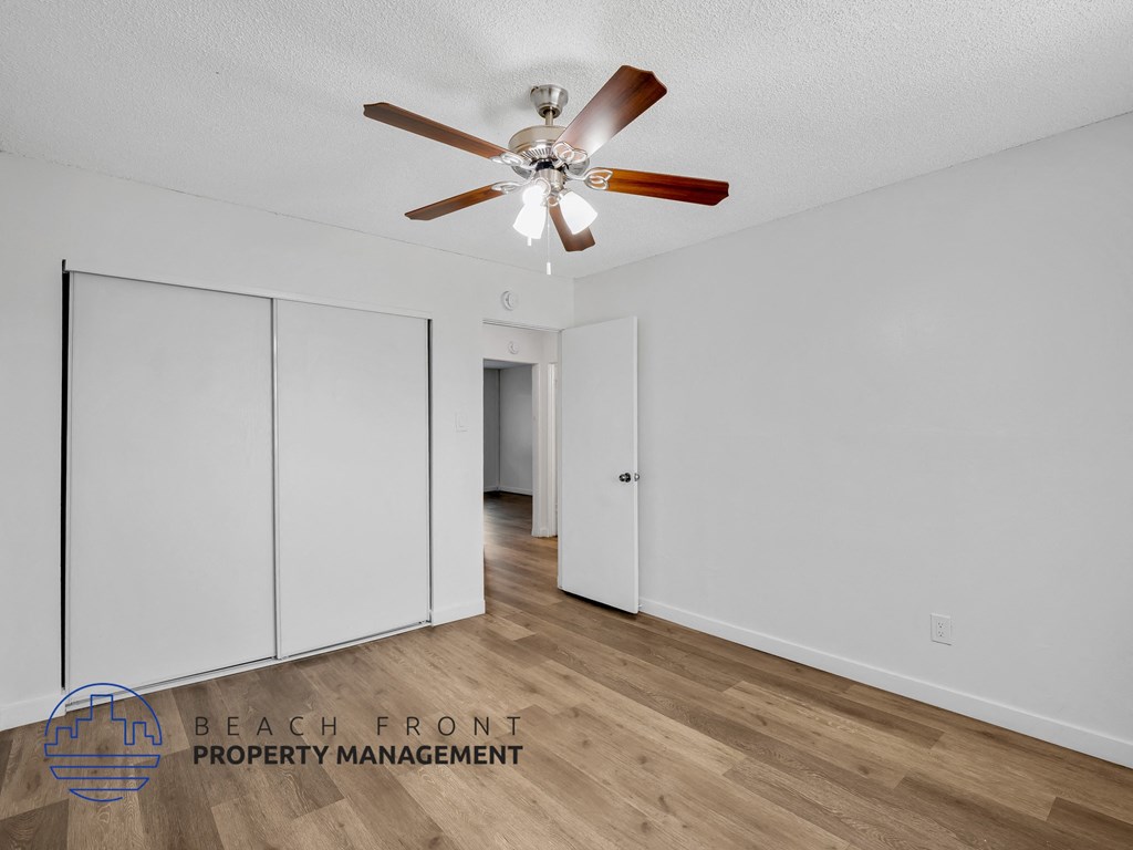 A room with a ceiling fan and sliding doors.