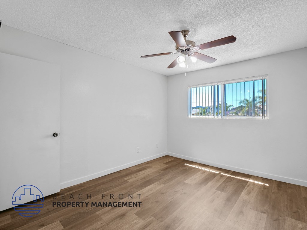 A room with a ceiling fan and a window with blinds.