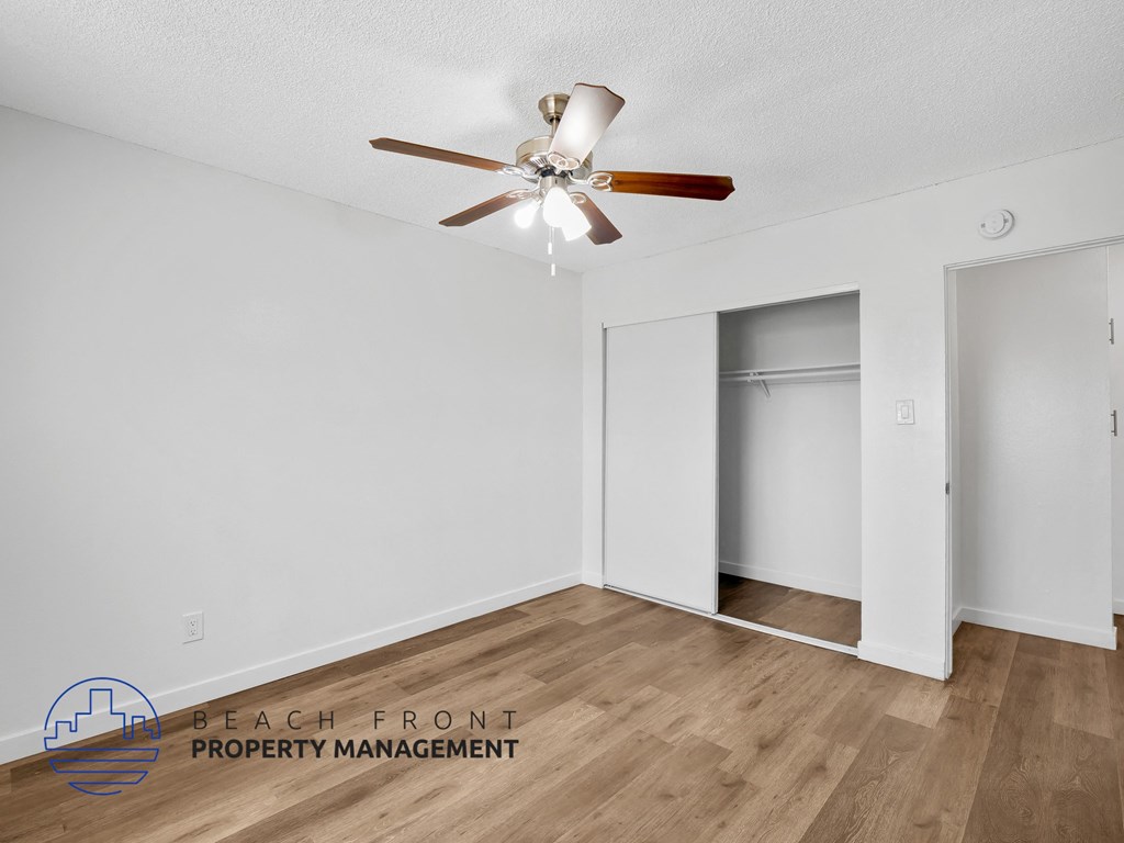 A room with a ceiling fan and wooden flooring.
