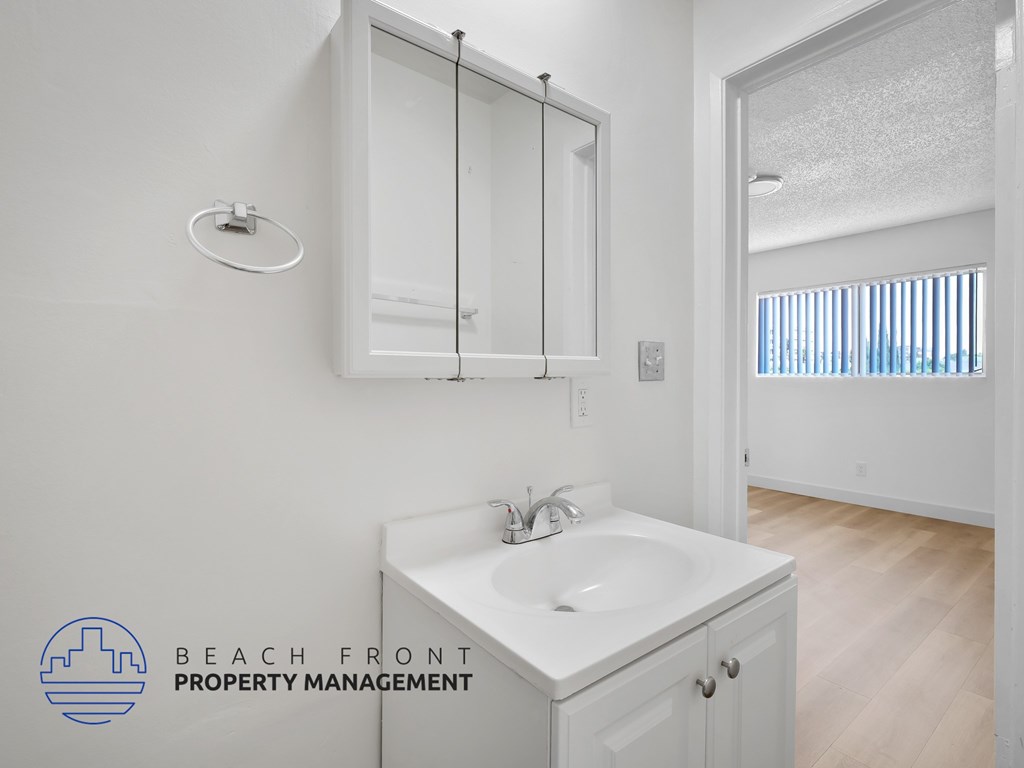 A white bathroom with a sink and mirror.