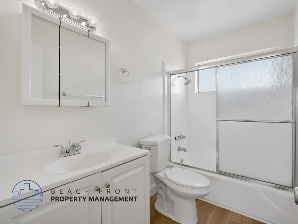 A white bathroom with a sink, toilet, and mirror.