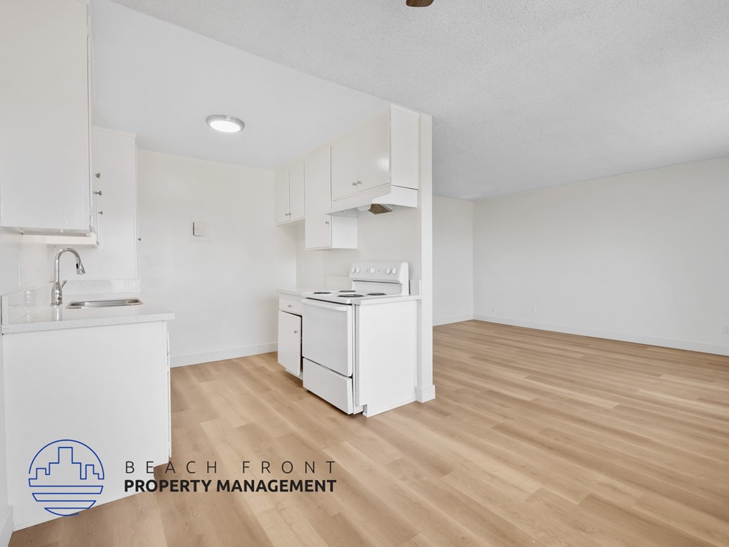 A kitchen with white appliances and wooden floors.