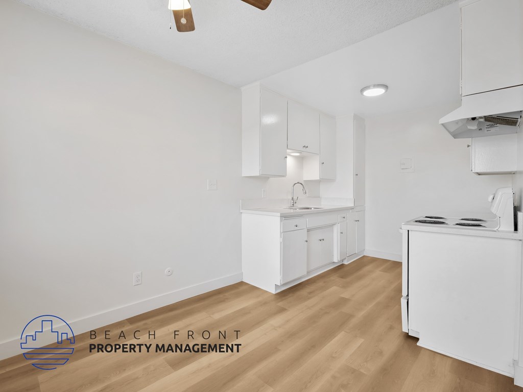 A kitchen with white cabinets and a wooden floor.