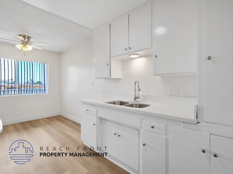 A kitchen with white cabinets and a wooden floor.