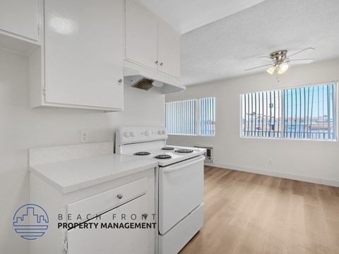 A kitchen with white appliances and cabinets with a logo for Beach Front Property Management.