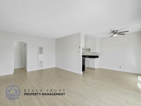 A spacious room with a ceiling fan and a kitchenette.