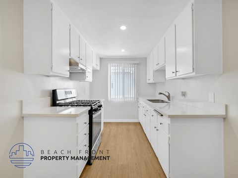 A kitchen with white cabinets and a wooden floor.