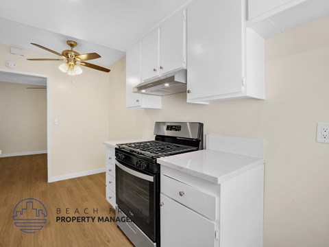 A kitchen with a stove top oven and a fan on the ceiling.