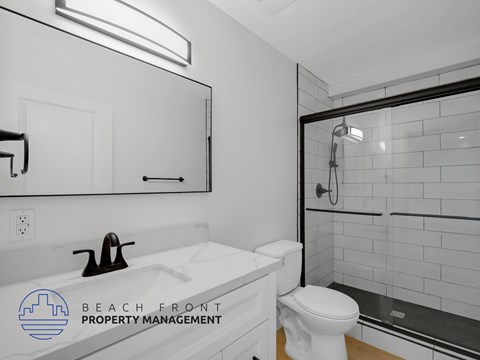 A white bathroom with a toilet, sink, and mirror.