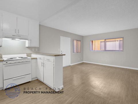 A kitchen with white cabinets and a wooden floor.
