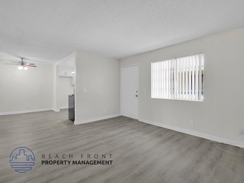 A spacious room with a ceiling fan and a window with blinds.