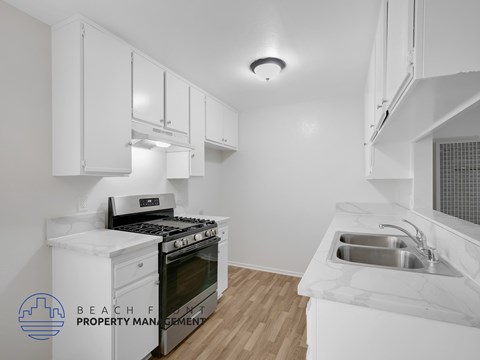 A kitchen with white cabinets and a stove top oven.