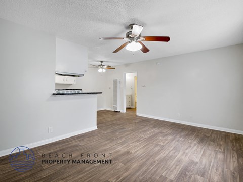 A spacious room with a ceiling fan and wooden flooring.