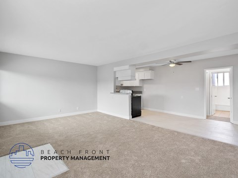 A spacious room with a carpeted floor and a ceiling fan, managed by Beach Front Property Management.