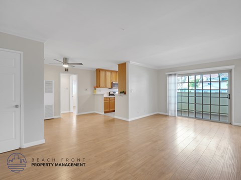 A spacious room with wooden flooring and a ceiling fan.