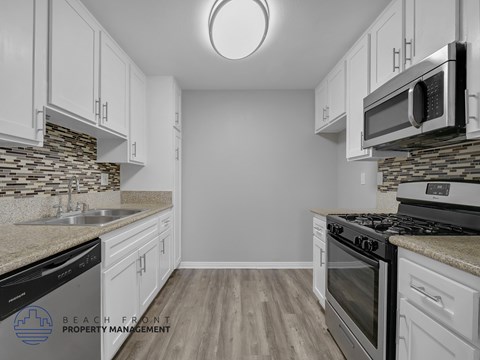 A kitchen with white cabinets and a stone backsplash.