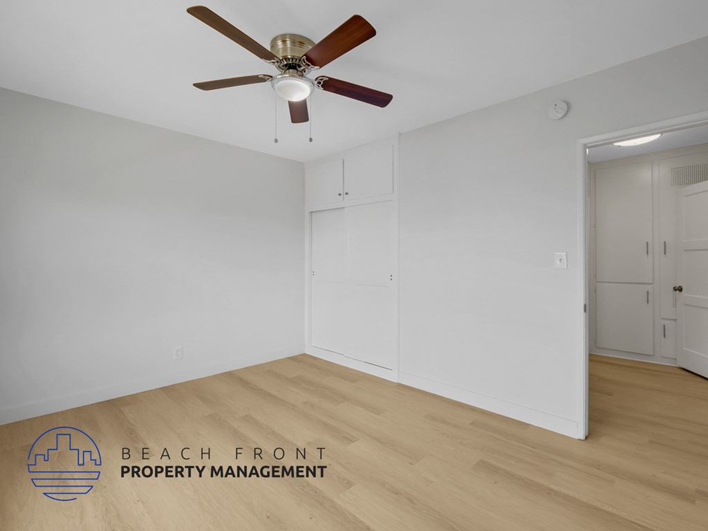 A room with a ceiling fan and wooden flooring.
