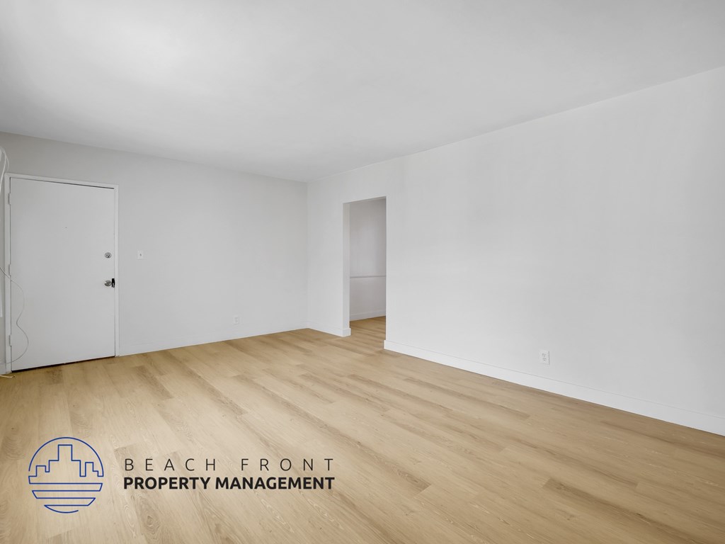 A room with wooden flooring and a logo for Beach Front Property Management.