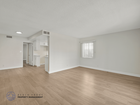 A sparsely furnished room with a logo for Beach Front Property Management in the bottom left corner.
