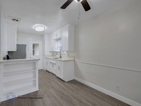 A kitchen with white cabinets and a ceiling fan.