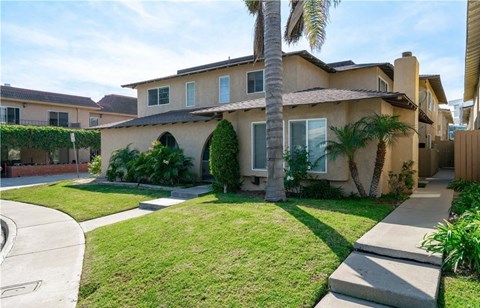 a house with a lawn and palm trees in front of it