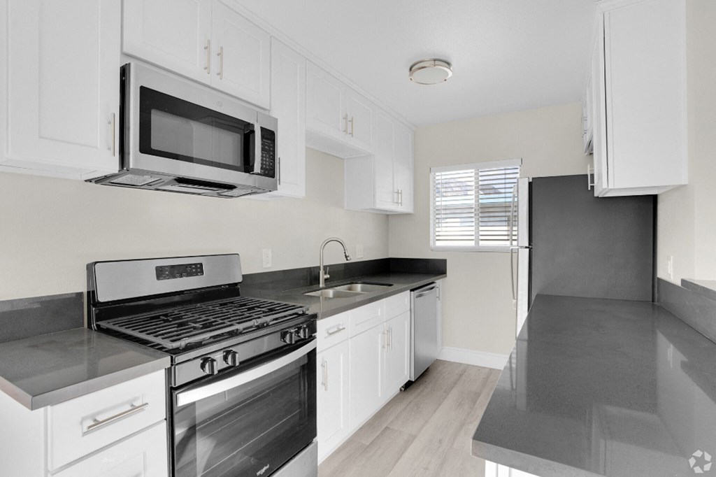 a kitchen with white cabinets and black counter tops and a stove and microwave