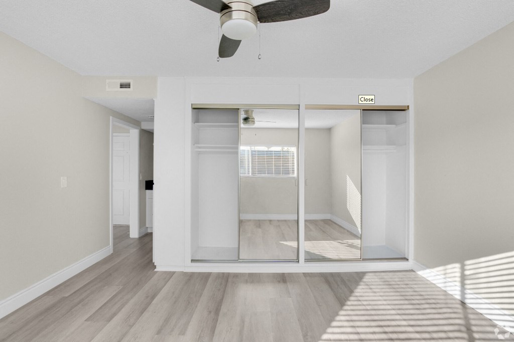 an empty room with a mirrored closet and a ceiling fan
