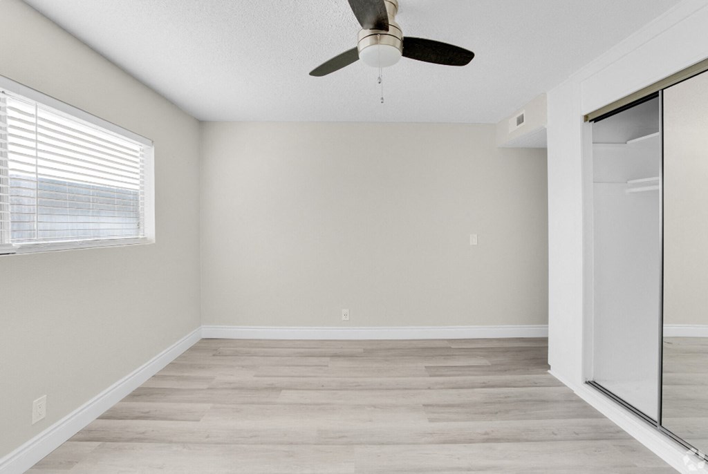 an empty room with a ceiling fan and a window