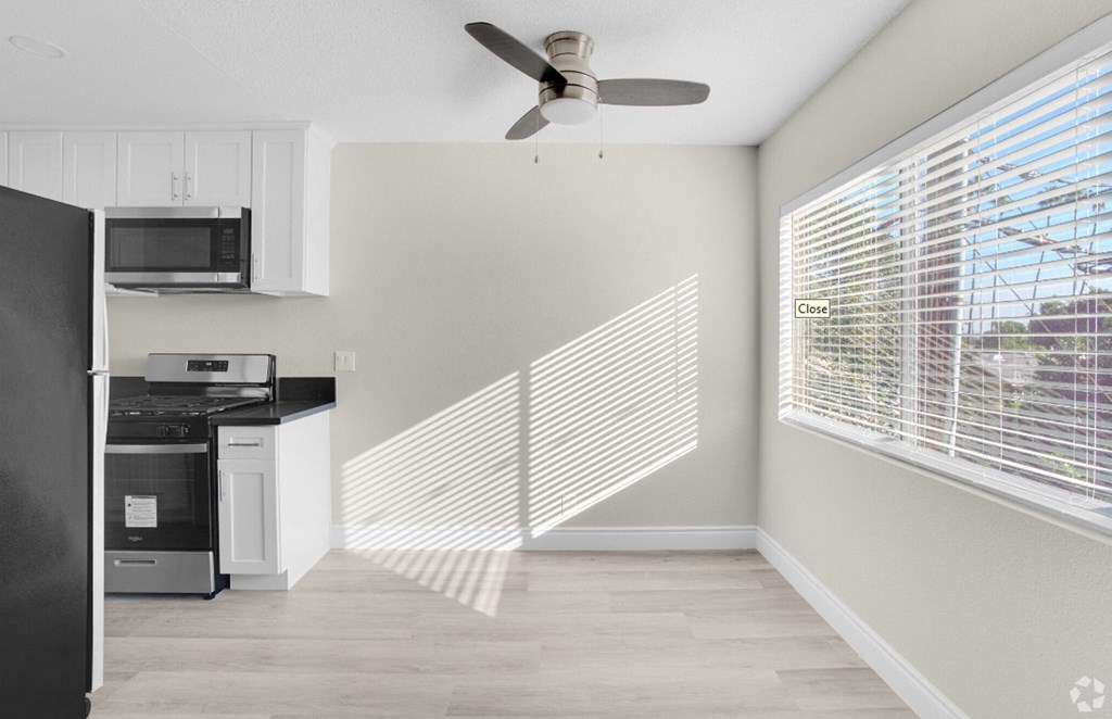 an empty kitchen with a large window and a ceiling fan