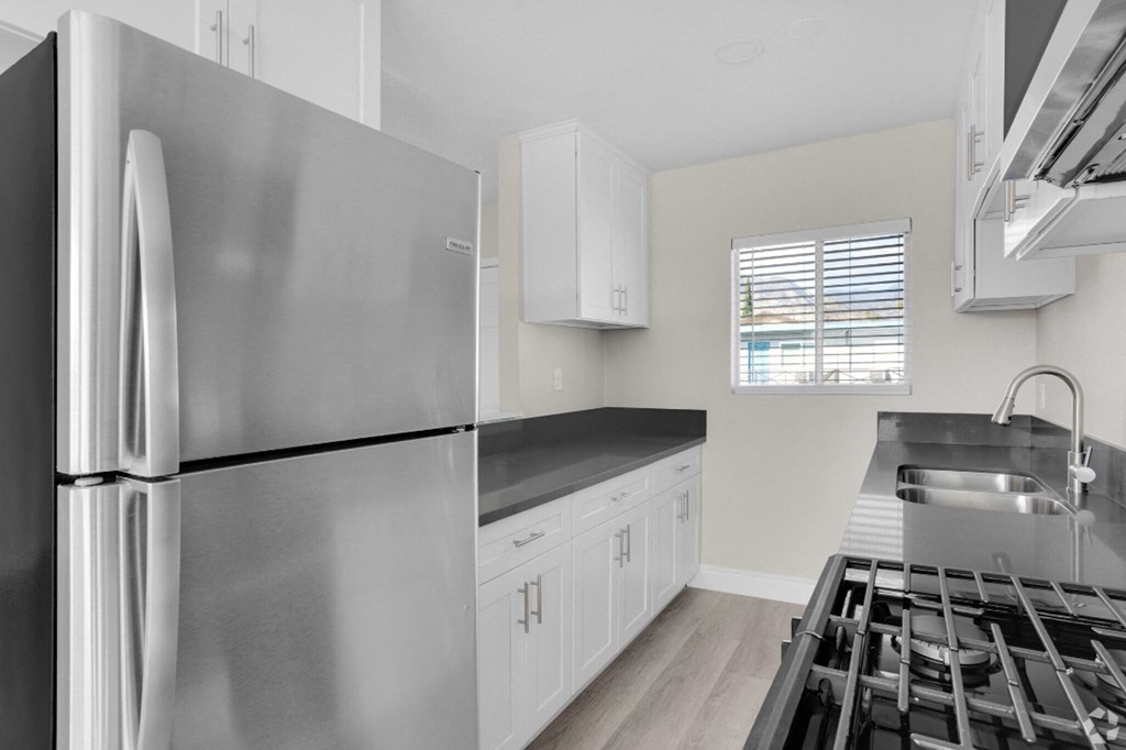 an empty kitchen with stainless steel appliances and white cabinets