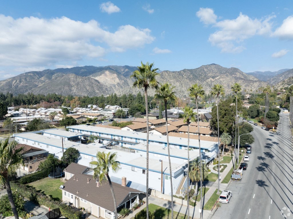 an aerial view of a large building with palm trees and a street
