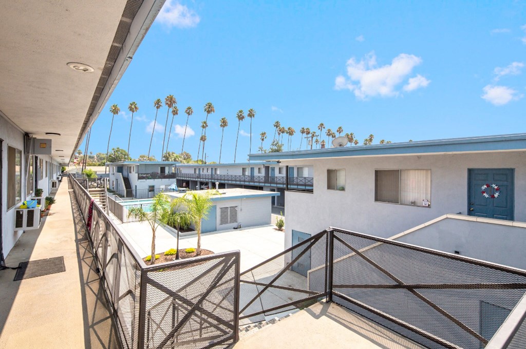 a balcony with a view of a building and palm trees
